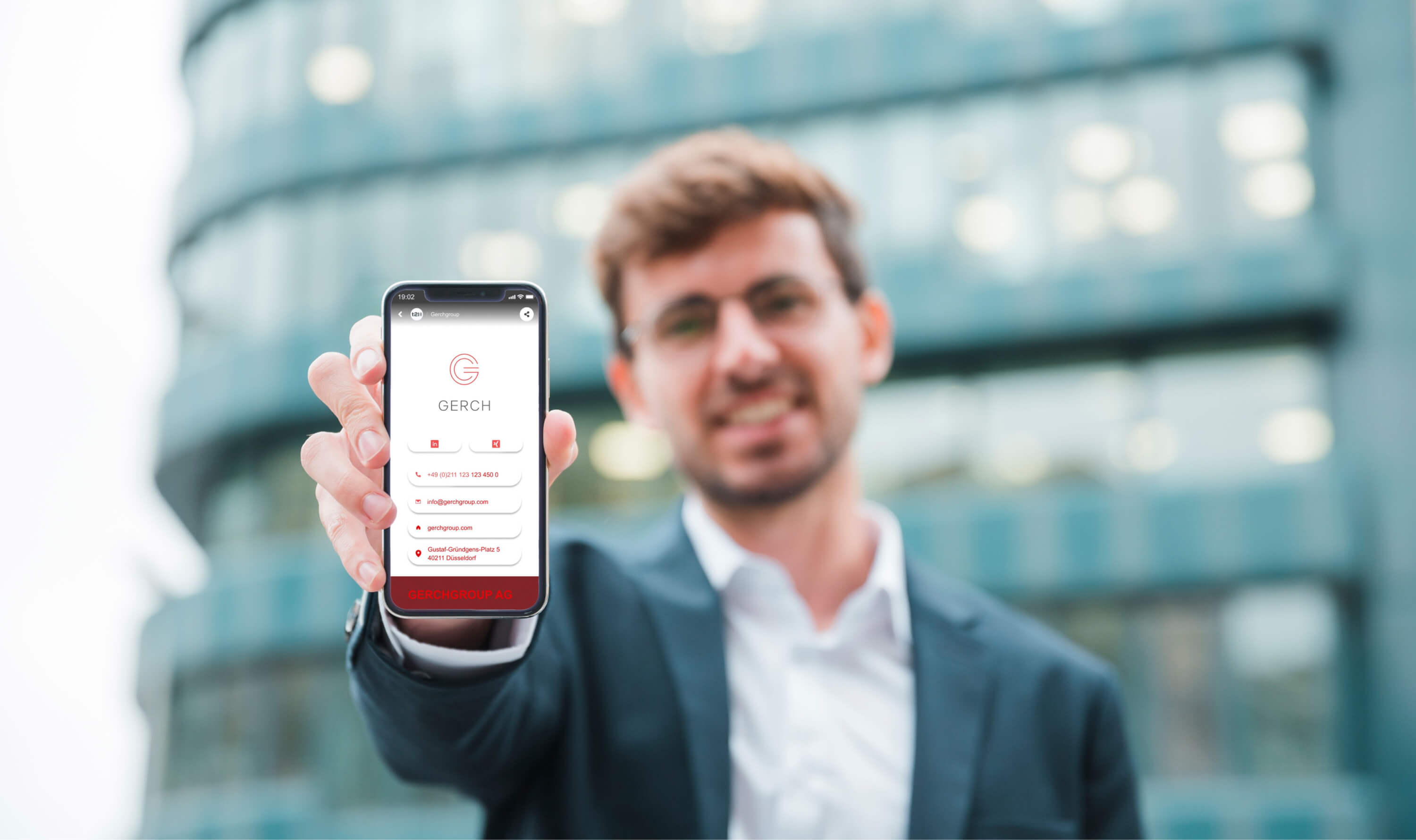 Mann, der ein smartphone in die Kamera hält, welches ein Kontaktprofil von Gerch zeigt, über tap2link geöffnet und durch sie erstellt . Zu sehen sind Logo, Persönliche Kontaktdaten und der Standort der Firma.