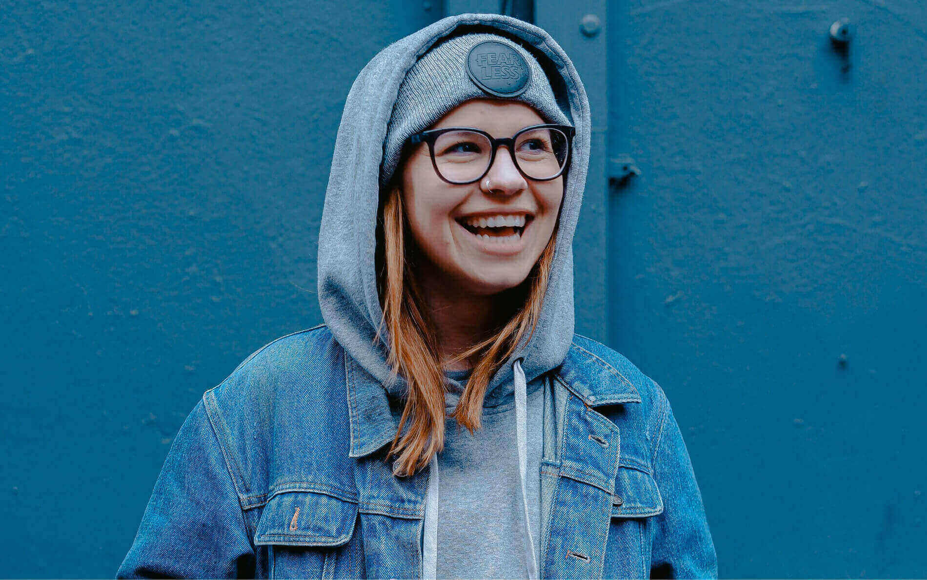 A smiling woman in a denim jacket holding her phone.